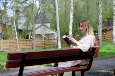 Parktaki genç kız elinde bir kitapla