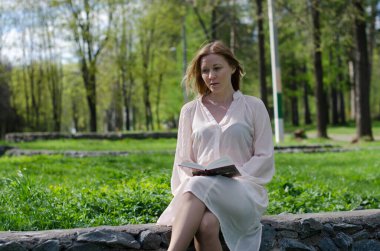 Parktaki genç kız elinde bir kitapla