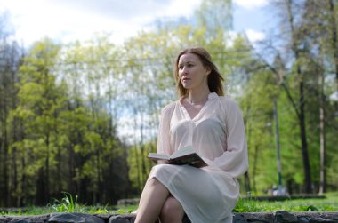 Parktaki genç kız elinde bir kitapla