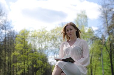 Parktaki genç kız elinde bir kitapla