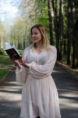 Parktaki genç kız elinde bir kitapla