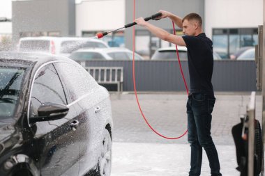 Aktif köpük kullanarak araba temizleme. Adam arabasını oto yıkamada yıkıyor.