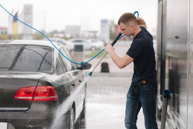 Araba yıkama. Shinig için yüksek basınçlı cilayı kullanarak araba temizlemek. Adam dışarıda arabasını yıkıyor.