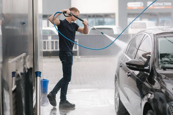 Car washing. Cleaning car using high pressure water. Man washing his car outdoor