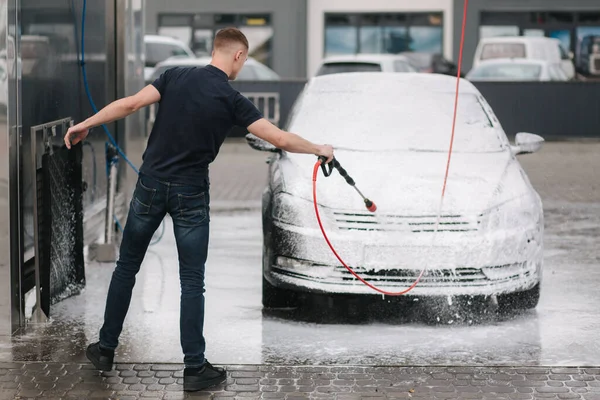 Aktif köpük kullanarak araba temizleme. Adam arabasını oto yıkamada yıkıyor. — Stok fotoğraf