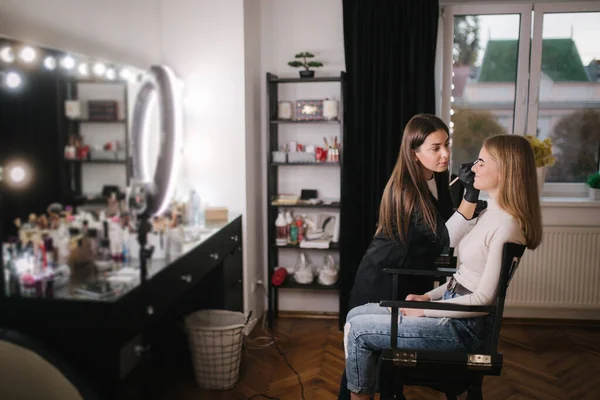 Brow master applies henna on eyebrows for beautiful blond hair woman