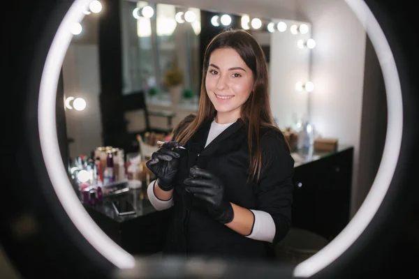 Ritratto di professionista donna sopracciglio master in veste nera con guanti neri uso pennello e hennè per le sopracciglia — Foto Stock