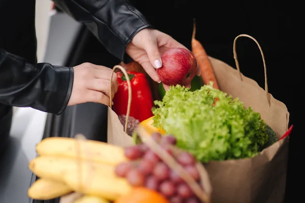 Крупный план продуктов в эко-упаковке в багажнике автомобиля. Руки женщины упаковки овощей и фруктов после доставки в супермаркет — стоковое фото