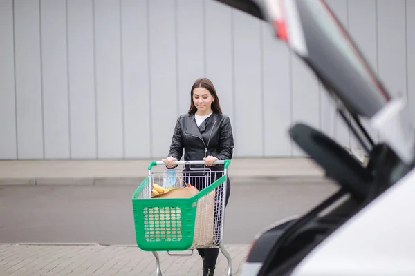 年轻迷人的女人开着电车从超市走到车上. — 图库照片