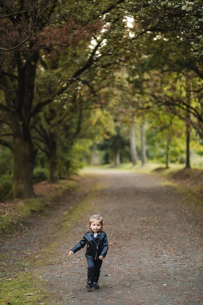 Menina feliz em jaqueta de couro andando na floresta de outono. Sorria e divirta-se — Fotografia de Stock