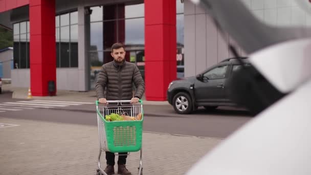 Guapo llevando comestibles de un supermercado desde el carro hasta el camión. Paquete artesanal — Vídeo de stock