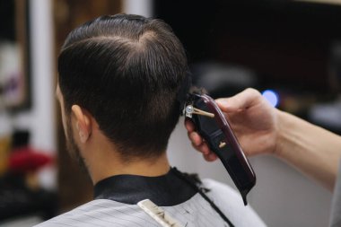 Erkekler Güzellik Salonunda. Berber dükkanında erkek tıraşı. Yeni saç stili 2021. Profesyonel kuaför saç fırçalamak için saç makası kullanır.