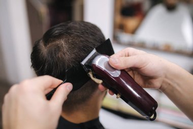 Erkekler Güzellik Salonunda. Berber dükkanında erkek tıraşı. Yeni saç stili 2021. Profesyonel kuaför saç fırçalamak için saç makası kullanır.