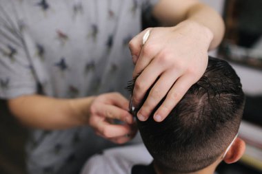 Berber dükkanında saçını makas kesen bir adam. Berber makas kullanır ve koronavirüs salgını sırasında maske takar. Profesyonel berber evde çalışıyor. Covid-19 karantina