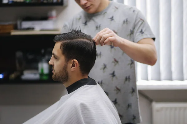 Нахабний чоловік підстригається від перукаря, сидячи в перукарні.. — стокове фото