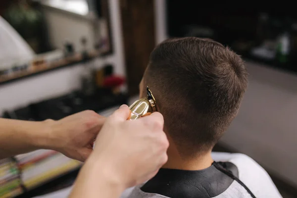 Peluquería profesional utiliza un cortador de pelo para flecos cabello para un hombre portador guapo. Peluquería — Foto de Stock