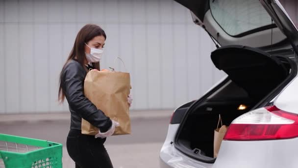 Groceries in females hand by the car truck. Woman in protective mask and disposable gloves. Fresh fruits in eco paket. Food shopping during coronavirus Covid-19 quarantine — Stock Video