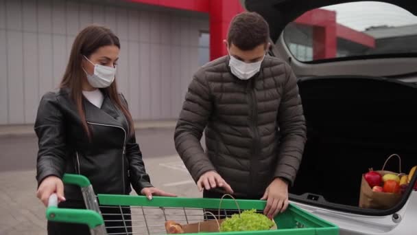 Mari et sa femme en masque de protection après avoir acheté de la nourriture dans une épicerie ou un supermarché pendant la quarantaine. Vue latérale. Shopping alimentaire pendant la quarantaine du coronavirus Covid-19 — Video