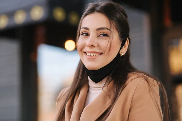 Portrait of beautiful woman with black protective mask on chin. Woman pulled off face mask