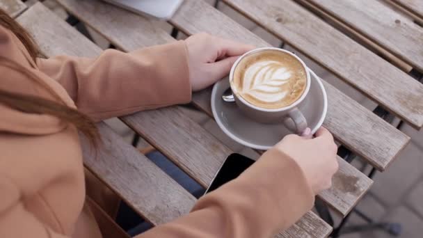 Tutup tangan wanita mengambil cangkir dengan cappuccino luar di kafe, selama karantina — Stok Video