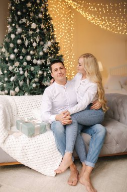 Mutlu koca portresi ve güzel karısı Noel tatillerinde evde kucaklaşıyorlar.