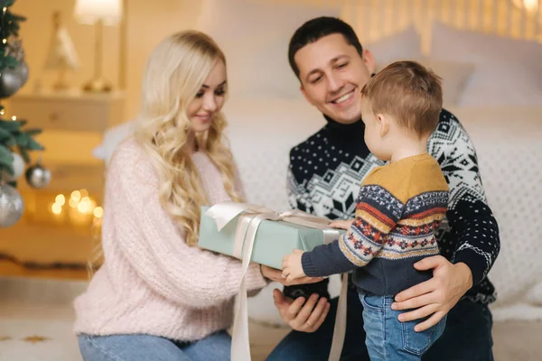 Glückliche Mama, Papa und kleiner Sohn beschenken sich gegenseitig. Liebevolle Umarmungen, Urlaubsmenschen. Zusammengehörigkeitskonzept. Weihnachtsfamilie — Stockfoto