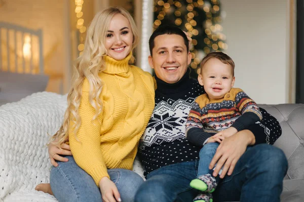 Retrato de pai, mãe e filho sentados em um treinador em casa perto da árvore de Natal, todos estão sorrindo. Família de Natal. Felicidade — Fotografia de Stock