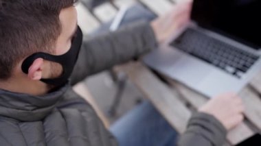 Yüzü maskeli yakışıklı bir adam kafede oturuyor ve dizüstü bilgisayarla çalışıyor. Adam salata alır. Karantinaya alın. Covid 19