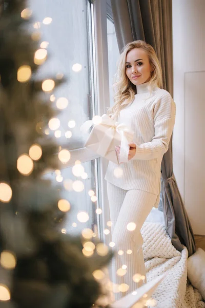 Portret pięknej blond włosy kobiety w pullover otwarty prezent na czas Bożego Narodzenia. Elegancka kobieta przy choince. Atrakcyjna kobieta. Świąteczny nastrój — Zdjęcie stockowe