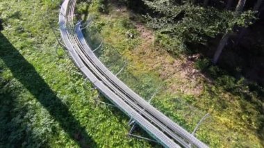 Güneşli bir sonbahar günündeki kayak merkezinin asansör kabinlerinin manzarası. Yeşil çimlerin üzerinde kaldırma hareketi. Ormanda yavaşça teleferik hareket ediyor. Tatil turizmi tatili kavramı