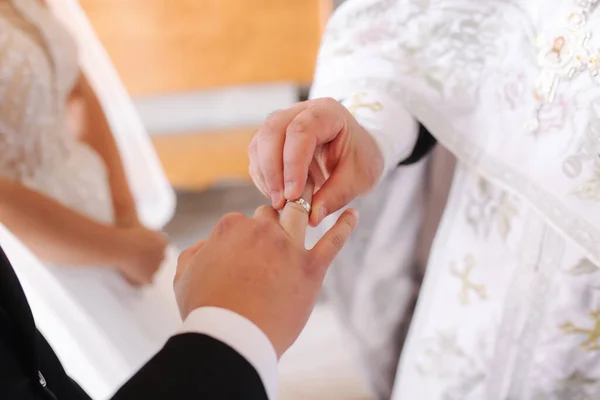 Κοντινό πλάνο του γαμπρού και της νύφης βάζουν τα δαχτυλίδια τους στο δάχτυλο στην εκκλησία — Φωτογραφία Αρχείου