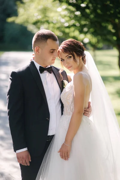 Mooie bruid met haar knappe bruidegom die buiten loopt op de trouwdag. Gelukkige pasgetrouwden — Stockfoto