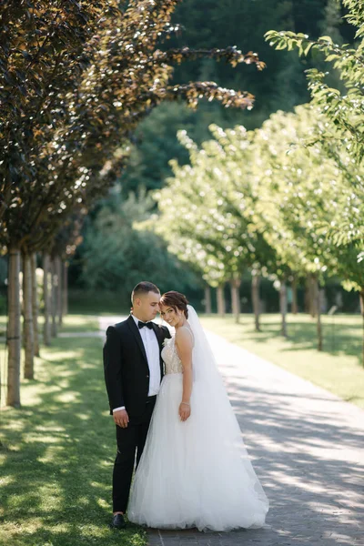 Schöne Braut mit ihrem hübschen Bräutigam, der am Hochzeitstag draußen spaziert. Glückliche Frischvermählte — Stockfoto