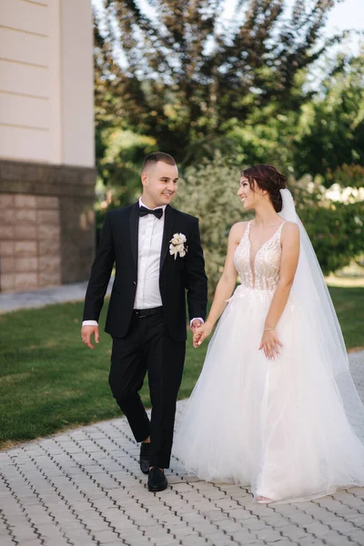 Прекрасная невеста со своим красивым женихом, выходящим на улицу в день свадьбы. Счастливых молодоженов. — стоковое фото