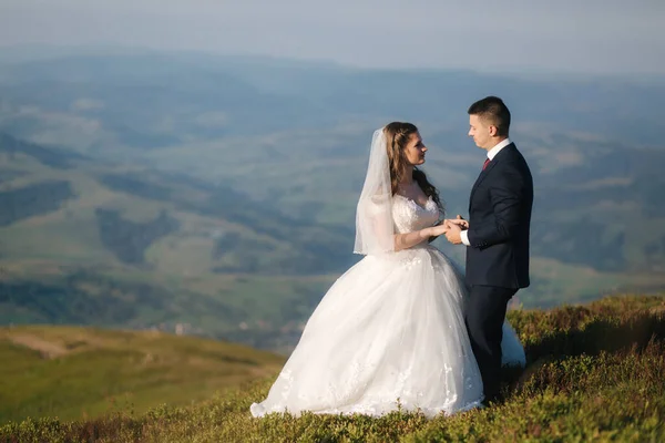 Svatební pár v horách. Nevěsta a ženich stojí na kopci — Stock fotografie