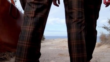Güzel köpekli iki neşeli adam sahilde taşların üzerinde oturup sohbet ediyor, mutlu eşcinsel çiftler iletişimi. Denizde Turistler. Arka plan