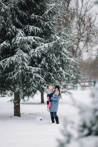 Bela jovem mãe com sua filha bonita no parque de inverno. Tempo de Natal — Fotografia de Stock