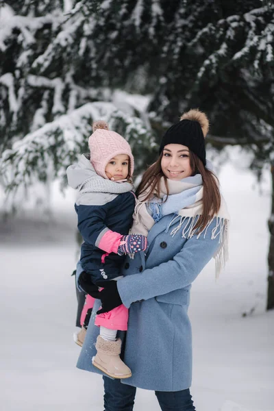Krásná mladá maminka se svou roztomilou dcerou v zimním parku. Vánoční čas — Stock fotografie
