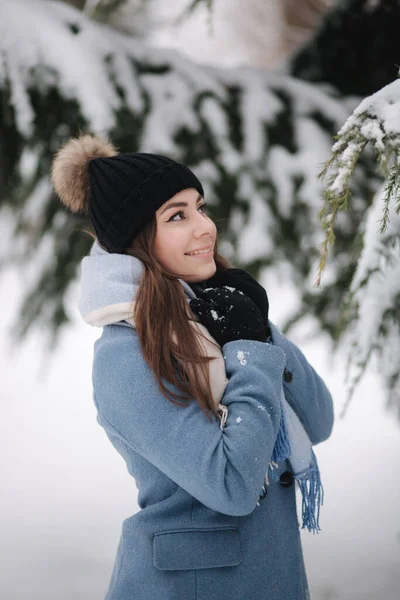 Csinos nő kék kabátban sétál az erdőben egy téli havas napon. Gyönyörű nő pózol fotós — Stock Fotó