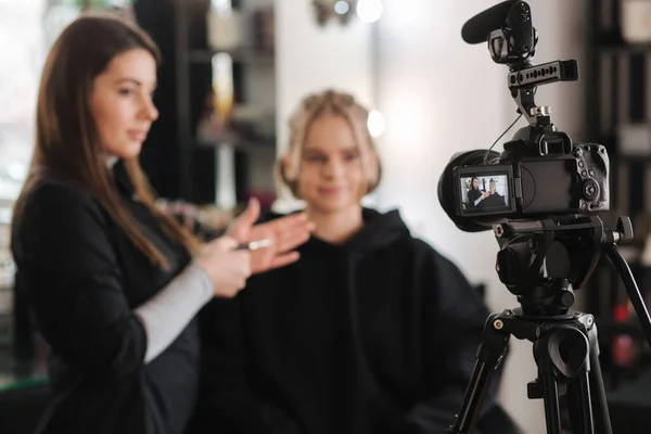 Mulher fazer maquiagem para mulher cabelo loiro atraente no estúdio. Foco seletivo da câmera digital com maquiador aplicando cosméticos para belo modelo — Fotografia de Stock