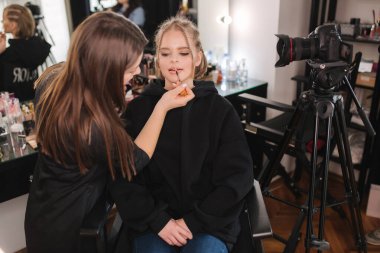 Stüdyodaki çekici sarışın kadın için makyaj yapıyor. Makyaj sanatçısının güzel bir model için kozmetik uyguladığı bir video.