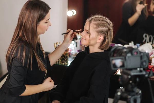 Vista lateral de maquillaje artista trabajo con hermosa modelo de pelo rubio en el estudio hasta que las películas de la cámara proceso de maquillaje. Blog de maquillador — Foto de Stock