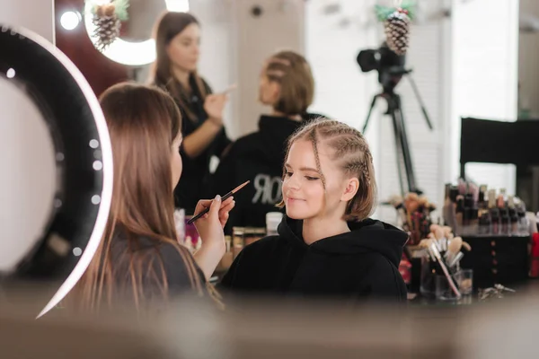 Kobieta zrobić makijaż dla atrakcyjnej blond włosy kobieta w studio. Wideo z makijażystą stosującym kosmetyki dla pięknej modelki — Zdjęcie stockowe