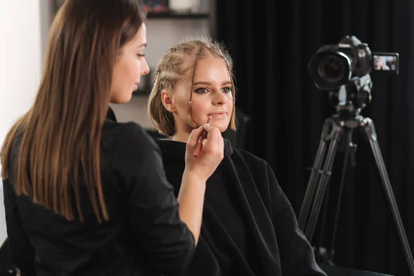 Красивая женщина красотка видеоблоггер делает косметическую демонстрацию макияжа со своей подругой в студии — стоковое фото