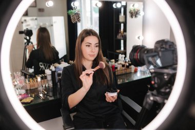 Makyaj sanatçısı kadın güzellik blogunda güzellik ürünlerini gözden geçiriyor. Kadın yüzük lambası kullan