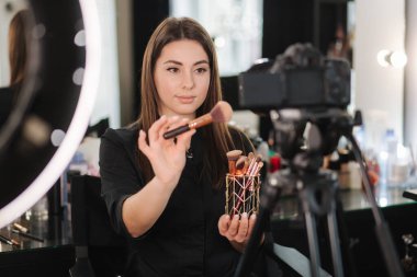 Makyaj sanatçısı kadın güzellik blogunda güzellik ürünlerini gözden geçiriyor. Kadın yüzük lambası kullan