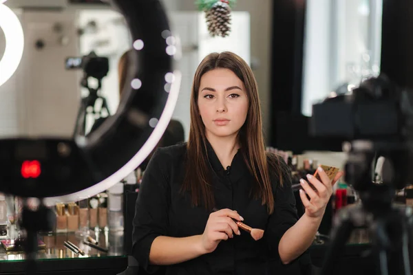 Jonge mooie vrouw en professionele schoonheid make-up kunstenaar blogger opnemen van make-up tutorial in de studio te delen op de website of sociale media. Vrouw gebruikt ringlamp en digitale camera — Stockfoto
