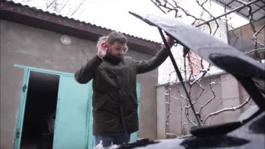 Adam arabanın kaputunu açtı ve arabaya ne olduğunu bulmaya çalışıyor. Kış açık havada