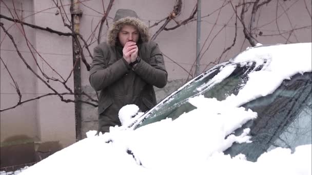 Snygg man rengör sin bil från snö med hjälp av händer. Vinter utomhus — Stockvideo