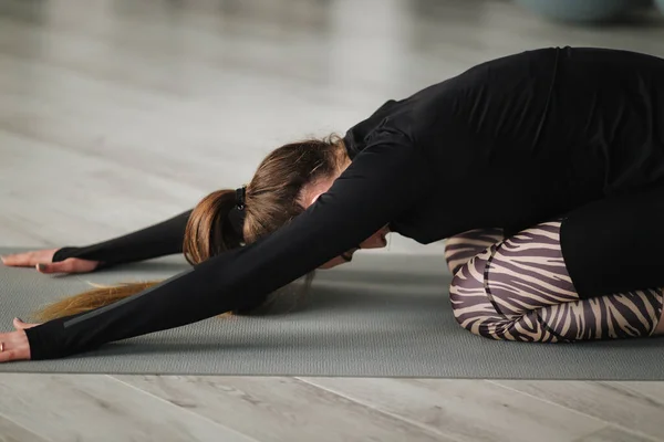 Young yoga master recording video content of her exercise for her online course with phone on tripod. Athletic female training in studio